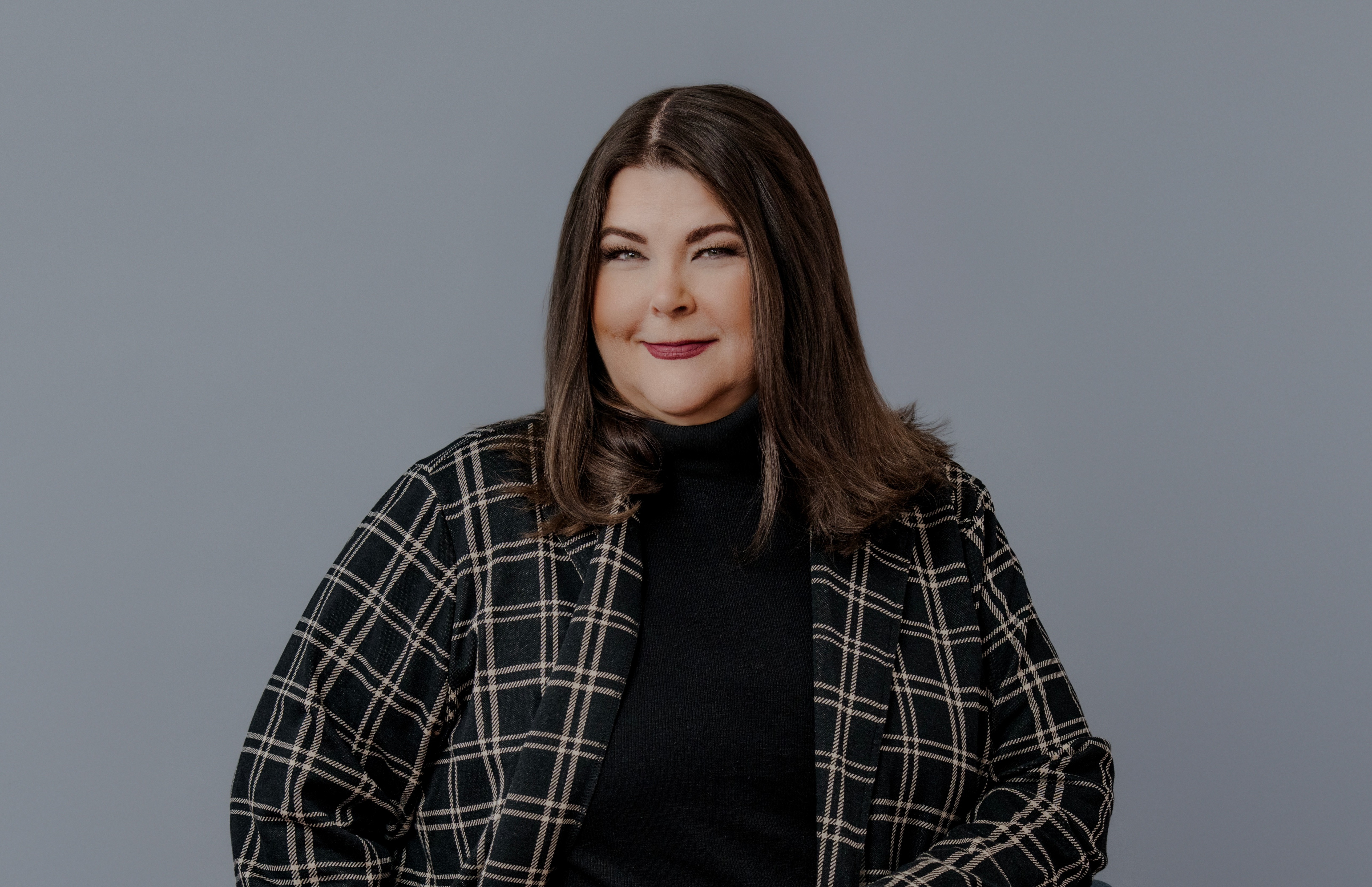 Headshot of a businesswoman in a suit in front of gray backdrop. 